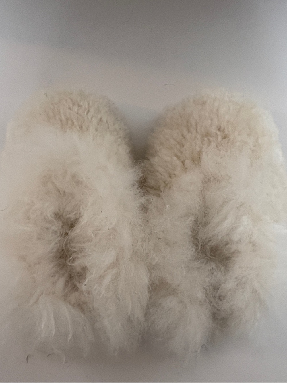 Ultra-soft cream slippers with a silky plush texture and suede-look sol